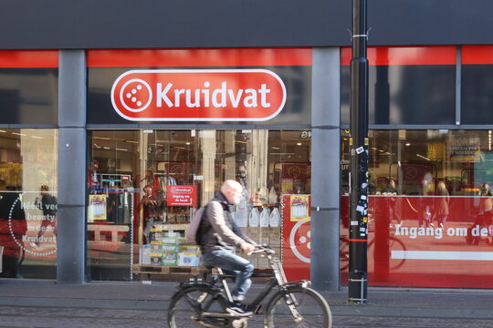 den haag, netherlands - march 18 2026: A cyclist rides past the Kruidvat store in Den Haag. The bright storefront displays a range of products.