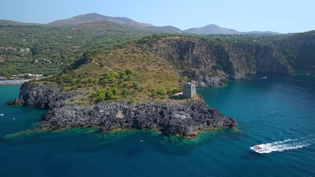 Marina di Camerota Cilento Italy 4K drone video. Torre del Zancale speedboat wake. Dynamic watchtower pivot and rental boat cruising bay travel b-roll stock footage