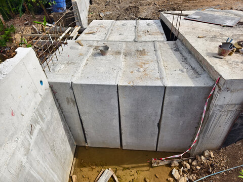 Concrete retaining wall installation beside small urban drainage channel during roadworks