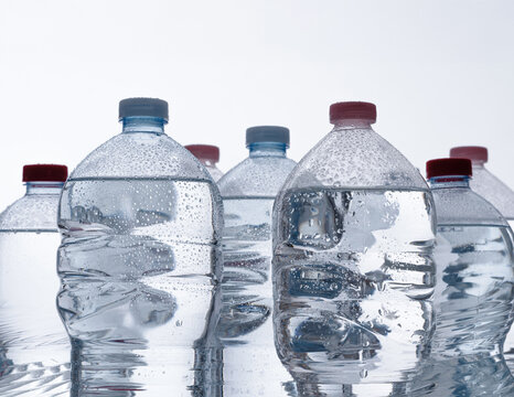 Cold plastic water bottles with drops reflecting on surface