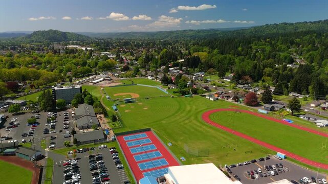 Aerial flight above a school campus with academic buildings sports fields and neighborhoods