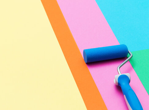 Paint roller on diagonal colorful background paper palette swatches