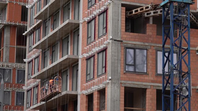 Construction workers ascending beside an unfinished multistory building, showing active high rise construction, urban development and building site operations