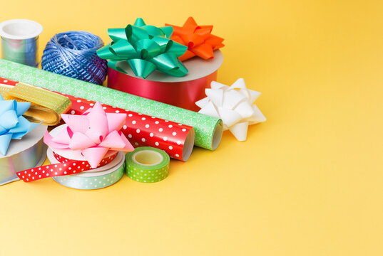 Colorful Gift Wrapping Supplies and Bows on Yellow Background