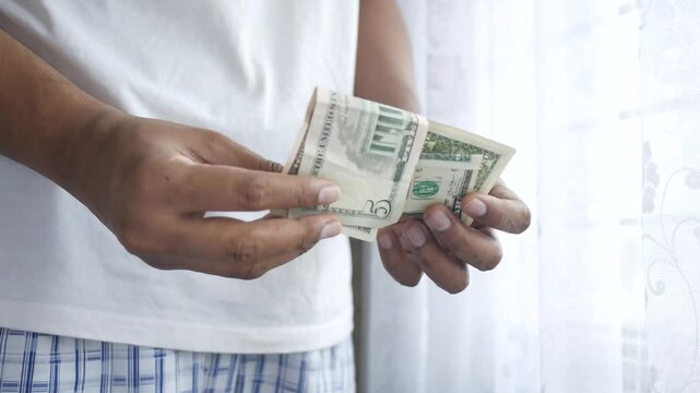 Person counting money closeup on a blurred background showing hands with dollar bills