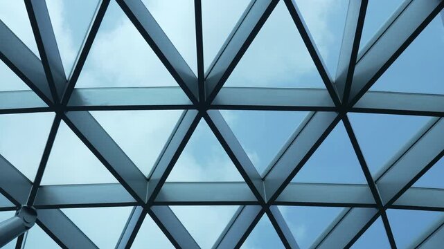 Geometric glass dome canopy featuring steel grid architecture against blue sky.