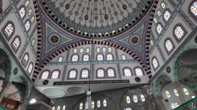 Ornate mosque dome interior view with intricate Islamic geometric patterns and stained glass windows
