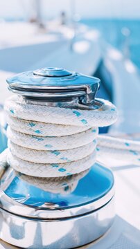 A gleaming chrome yacht winch tightly wrapped with white braided rope under bright sunlight. This close-up captures marine precision, luxury, and calm sailing vibes.