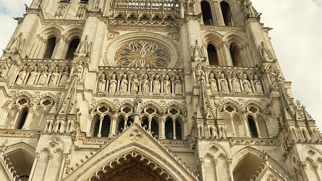 Amiens Cathedral entrance with gothic arches and rose window under cloudy sky