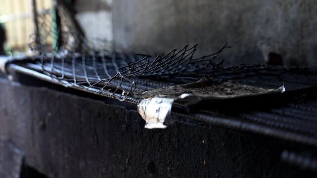 薄暗い作業場に積まれた鉄筋と金網、建設資材のクローズアップ（Rusty Rebar and Wire Mesh Stacked in a Dim Workshop）