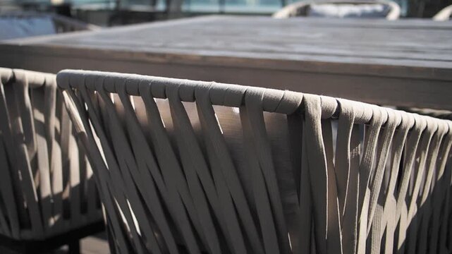 Close up slow motion of outdoor patio chairs with woven seats by wooden table