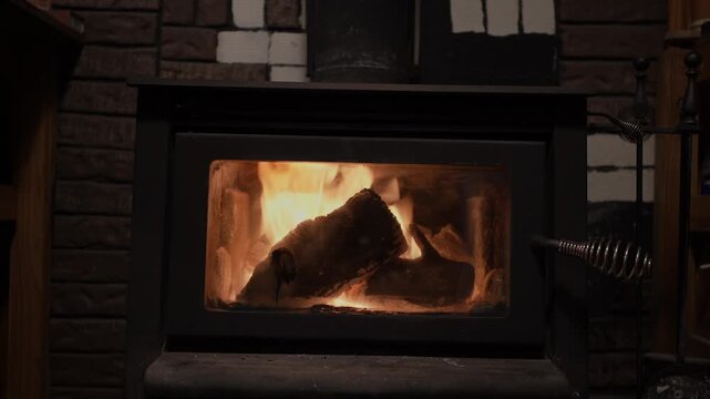 A cast iron wood stove radiates heat with burning logs visible through the glass door, creating a warm and inviting atmosphere