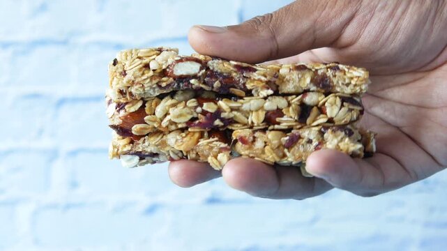 Hand holding stacked healthy granola bars with nuts and oats