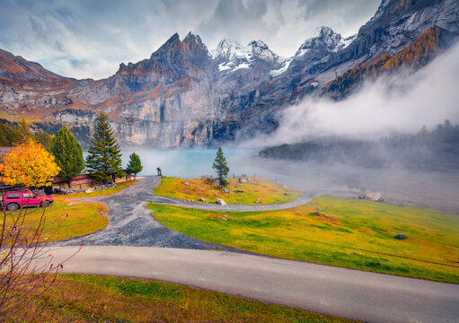 Picturesque autumn view of Oeschinensee Lake, Switzerland, Europe. Misty morning scene of Swiss Alps with Bluemlisalp peak on background.