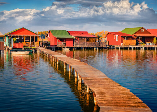 Exciting summer view of colorful fishing cabins connected to a lake by narrow wooden piers. Superb morning scene of Bokodi Floating Village, Hungary, Europe. Traveling concept background.