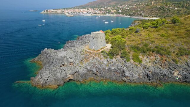 Torre del Zancale watchtower Marina di Camerota drone pass above rocky coast. Aerial overflight of historic coastal stone tower flying towards bay, Cilento Campania Italy 4K video.