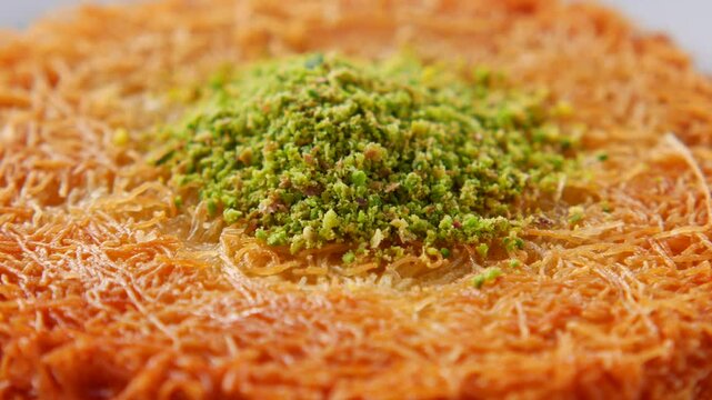 Close up rotating drone footage of sweet kunafa dessert topped with crushed pistachios