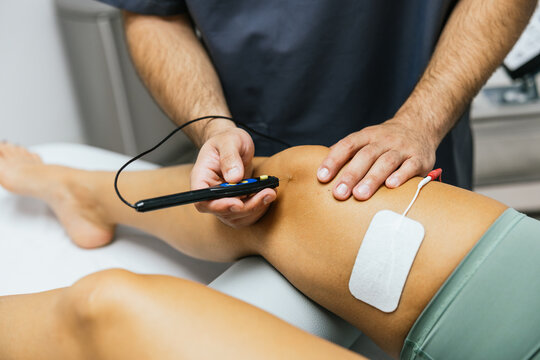 Physiotherapist performing percutaneous electrolysis on patient's knee