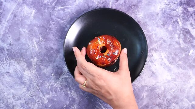Close up of hand arranging donuts on black plate sweet pastry dessert