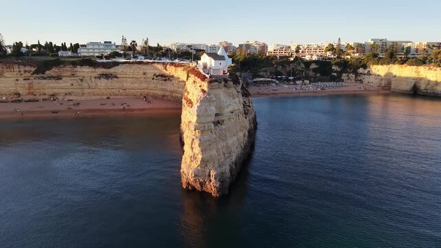Aerial view of Nossa Senhora da Rocha chapel and Algarve coastline at sunset in Portugal