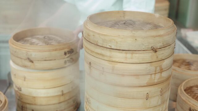Hot steam rising from stacked bamboo dim sum steamers in an Asian restaurant.