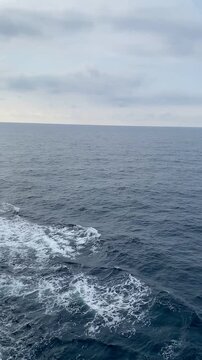 Deep blue sea water with foaming white waves created by moving ship