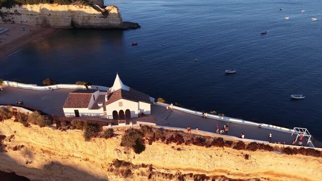 Aerial drone view of Nossa Senhora da Rocha chapel on coastal cliff in Algarve Portugal