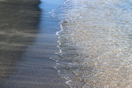 Aesthetics of sea surf with contrasting sand. Calm summer day on an exotic beach, vacation at the sea, relaxation, travel and unity with nature. Smooth movement of water on the coast