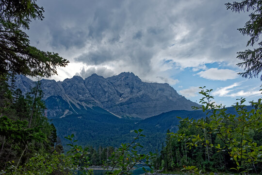 Mountain View Through Alpine Forest Framed by Dramatic Cloudy Sky Near Zugspitze