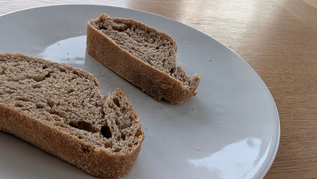 Angled close-up view of sliced rustic bread showing its textured crumb and crust on a plate.