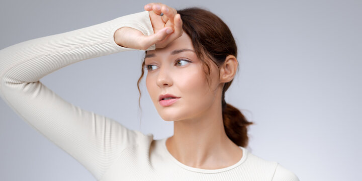 Tired Fitness Woman In White Sportswear Resting With Hand On Forehead