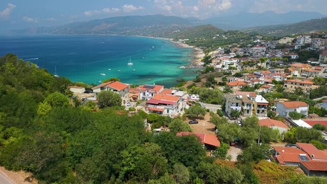 Palinuro town aerial drone flyover along winding road in Cilento Campania Italy. Vibrant coastal resort with orange roofs swimming pool and yachts in turquoise sea 4K