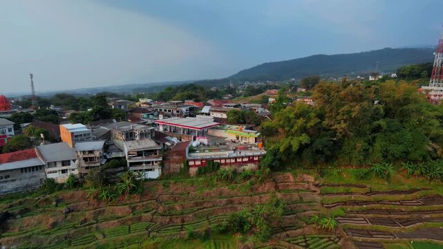 Aerial View of Terraced Farmland and Hillside Town with Telecom Tower and Gas Station