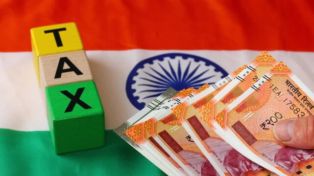 Taxes in India. Filing ITR and GST returns. Financial concept. Business background. Counting Indian rupees over the Indian flag and the word "TAX".