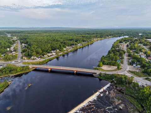 Aerial View of River Bridge and Dam Overlooking Small Town of Howland, Maine with Forested Rural Landscape