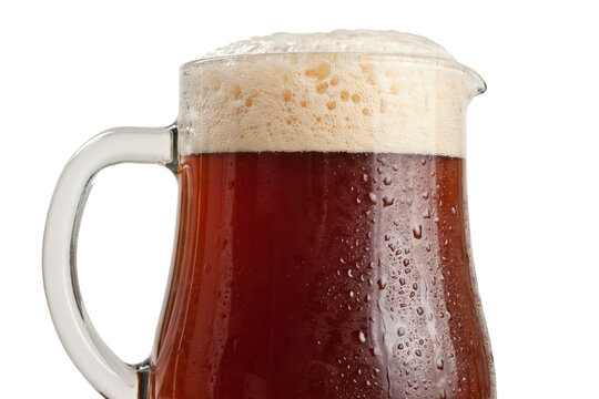 A large glass pitcher filled with dark amber beer and thick white foam head isolated on a transparent background