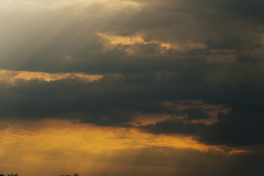 View of Doxey Marshes at sunset with dramatic dark clouds and golden light rays breaking through the sky in Stafford, England, United Kingdom.
