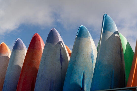 View of colorful kayaks lined up in a row against a bright blue sky in Aberdyfi, Wales, United Kingdom.