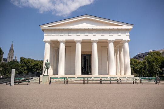 Facciata del Tempio di Teseo (Theseustempel) in stile neoclassico nel parco Volksgarten a Vienna, incorniciata da un giardino di rose fiorite in una giornata estiva di sole, Austria