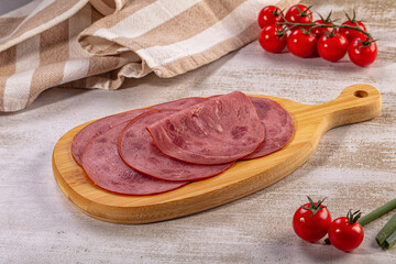 Sliced deli meat on wooden cutting board with cherry tomatoes and striped cloth © Andrei Starostin