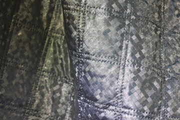 Obraz premium Gray textured fabric with stitched geometric pattern and metallic sheen creating abstract textile background