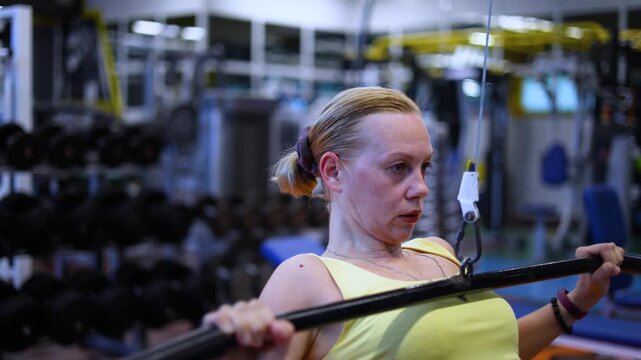 Join this fitness enthusiast as she expertly performs pulldown reps on a lat machine, emphasizing controlled movements to effectively target her lats and enhance her overall strength.