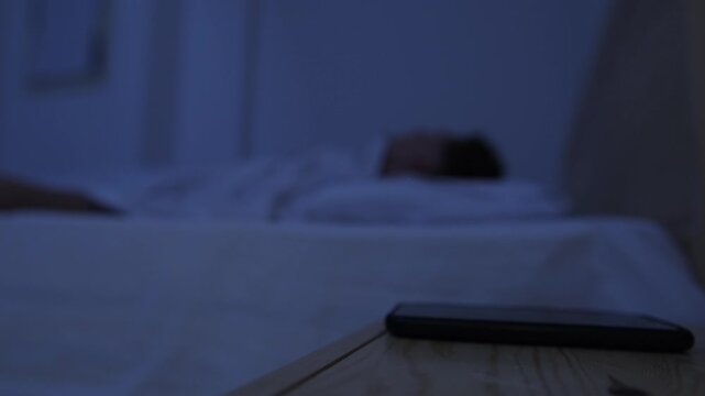 Man unable to fall asleep after putting smartphone away, picks it up again and doomscrolls at night, trapped in cycle of screen use and insomnia