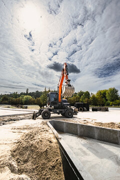 Excavator operates at a rental site, moving dirt for landscaping project. The machine digs and shapes the ground in preparation for further work