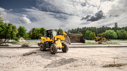A loader moves dirt while a bulldozer prepares the area at the landscape site. Both machines are engaged in site preparation and earth moving tasks © Anoo