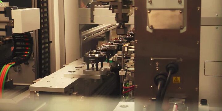 Automated industrial machinery operating within a factory setting to assemble metal components using precision robotics and electronic sensors for high volume production in a busy manufacturing