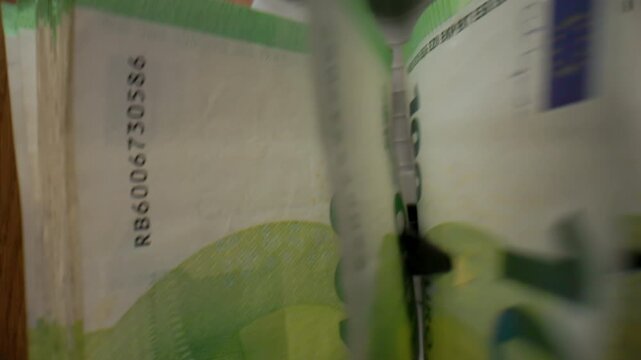 Extreme macro shot of 100 Euro banknotes in a cash counting machine