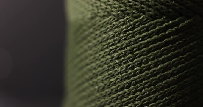 Close-up of green knitted fabric with visible stitch pattern, textile material.
