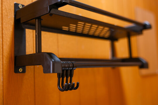 Wooden wall mounted metal coat rack with shelf and hooks creates organized home storage in warm interior, offering practical hanging space for coats, bags, and daily accessories