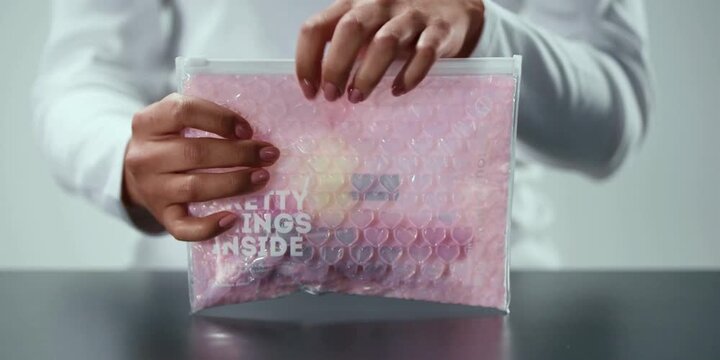 A woman holds a padded shipping pouch containing items meant for delivery as she carefully handles the protective package prepared for safe transport to customers across the country this day